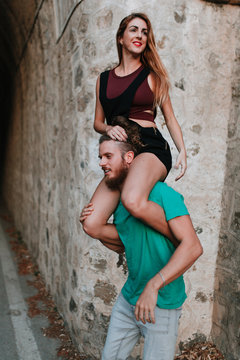 Man carrying his girlfriend on his shoulders. Alternative couple.