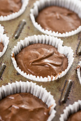 Raw chocolate cup cakes mixture in the cup cakes papers ready for baking