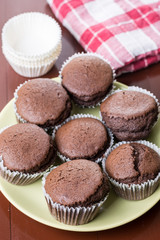 Fresh baked chocolate cup cakes served on the plate with kitchen dishtowel in the background