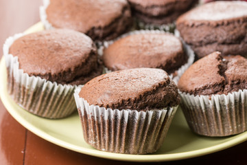 Fresh baked chocolate cup cakes served on the plate with kitchen dishtowel in the background
