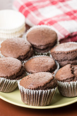 Fresh baked chocolate cup cakes served on the plate with kitchen dishtowel in the background