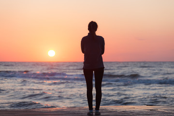 Lonely girl standing on the sunrise beach