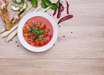 Chicken curry with raw ingredients on wooden background, top view of chicken panaeng curry, delicious of thai food. Copy space.