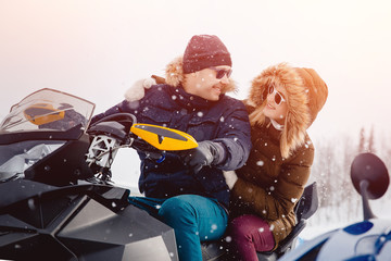 Snowmobile. A couple of girlfriends and a guy on a snowmobile laugh. Concept travel in winter.