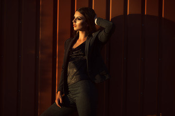Portrait of pretty serious business woman is wearing black official clothes near wooden wall
