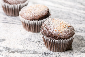 Chocolate brownies cup cakes with powdered sugar on the grey granite background