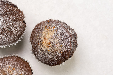 Flat lay above chocolate brownies cup cakes with powdered sugar on the white marble background