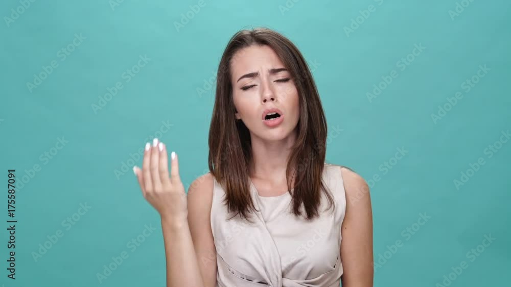 Sticker surprised upset brunette woman in t-shirt looking at the camera over turquoise background