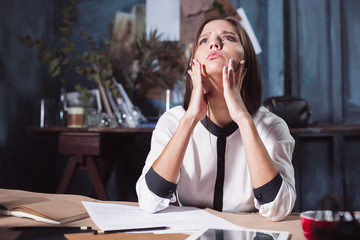 Young frustrated woman working at office desk in front of laptop