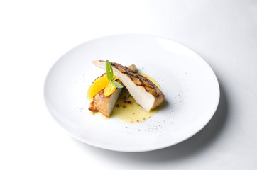 Grilled chicken fillet with orange mint sauce on a white plate