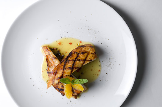 Grilled chicken fillet with orange mint sauce on a white plate