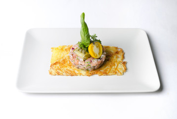 Tartar from trout on a potato pancake on a beige dish