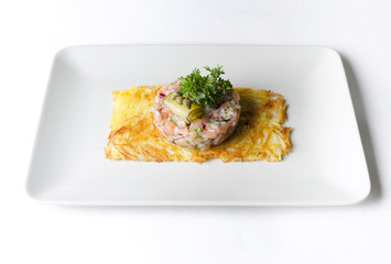 Tartar from trout on a potato pancake on a beige dish