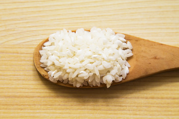 wooden spoon with rice on wooden table
