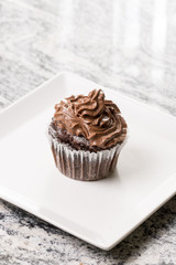 Chocolate cup cake with ganache chocolate cream on the white square plate