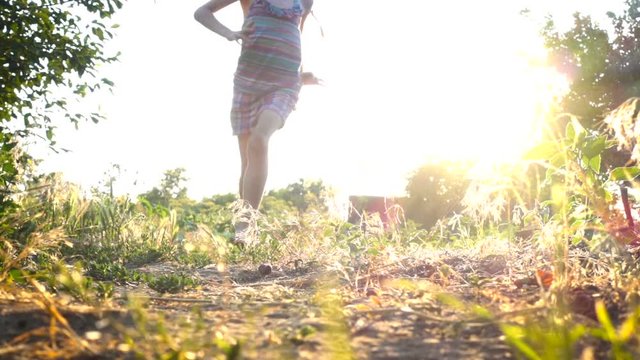 child girl running on the ground with bare feets at the sunset time