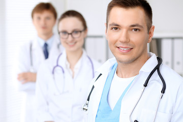 Fototapeta premium Cheerful smiling male doctor with medical staff at the hospital