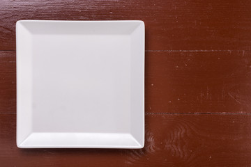 Flat lay above white square plate on the wooden brown board table