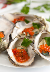 Fresh opened oyster on plate with caviar and green 