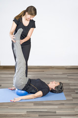 Trainer helps a woman senior in her pilates exercices