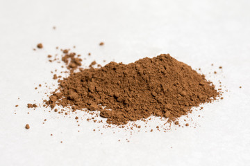 Brown cocoa powder isolated above white marble background table