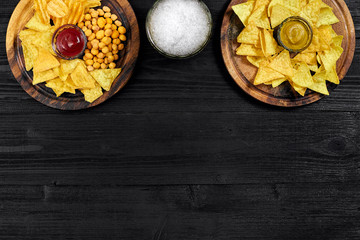 Lager beer and snacks on black wooden table. Nuts, chips. Top view with copyspace