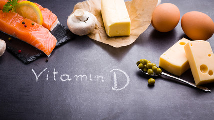 Black slate table with product rich in vitamin D and omega 3. Written word vitamin D by white chalk.