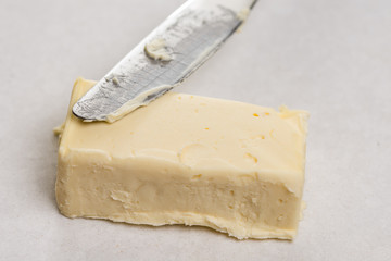 Slice of butter with kitchen knife on the white marble background table