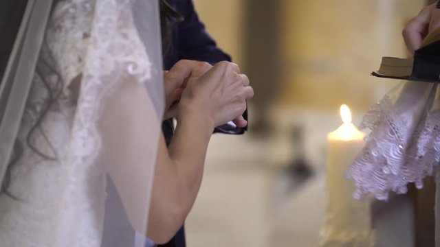 Priest put on wedding rings to bride and groom hands in church