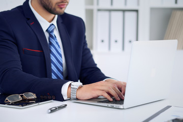 Businessman working by typing on laptop computer. Man's hands on notebook or business person at workplace. Employment  or start-up concept