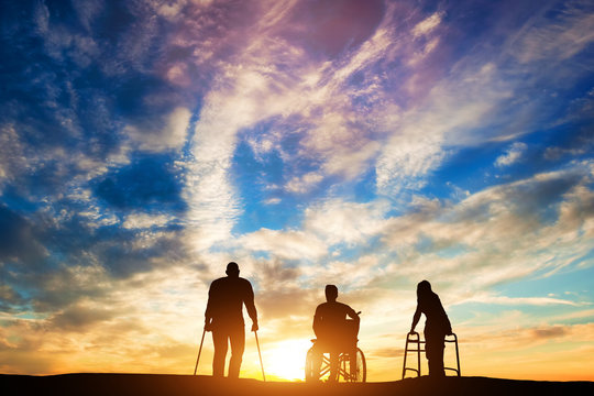 Three disabled people at the sunset.