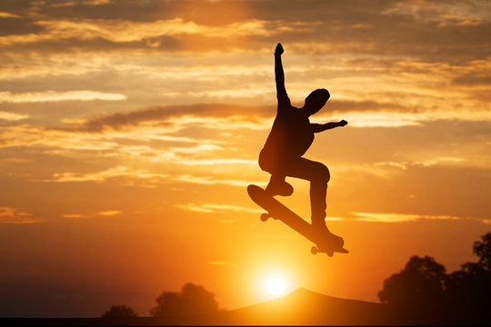 Skateboarder jumping at sunset.