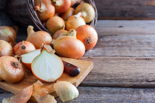 Vintage onions on a wooden table with a cut onion on a board, vitamins, horizontal, copy space