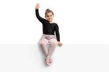 Small ballerina sitting on a panel and waving
