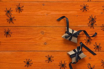 Decorative black spiders and gift boxes on orange wooden boards. Background for Halloween.