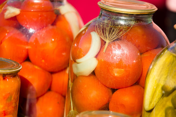 canned cucumbers and tomatoes in glass jars