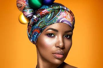Beautiful woman colorful portrait. Young afro girl posing on yellow background with colorful material on head. Ethnic style. © demidenko
