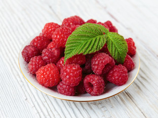 Raspberries in a bowl on a wooden white table