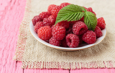 Raspberries in a bowl on a wooden table pink