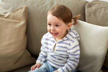 happy smiling baby girl sitting on sofa at home