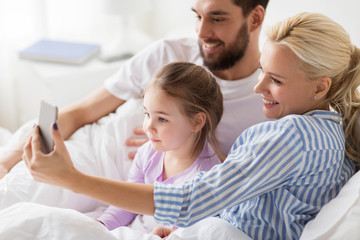 Obraz premium happy family taking selfie by smartphone at home