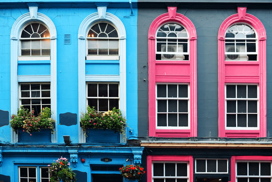 Fachada en colores azul y rosa, con ventanas alargadas pintadas a juego.