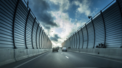 Cars on the sound-absorbing tunnel at the asphalt road. Metal structure with plastic parts. Modern...