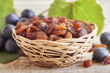 Raw raisins (dried grape) in woven basket on wooden background