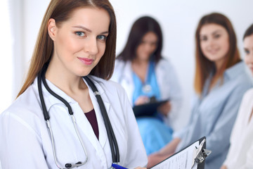 Young beautiful female doctor smiling to patient while consulting her