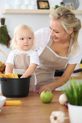 Mother and little daughter are cooking in the kitchen. Spending time all together or happy family concept