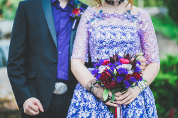 wedding bouquet in bride's hands in purple dress near groom