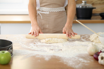 Female hands making dough for pizza or bread while using rolling pin. Baking concept