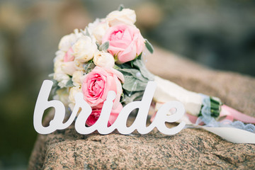 Beautiful bouquet and word bride on rock. Beach wedding concept
