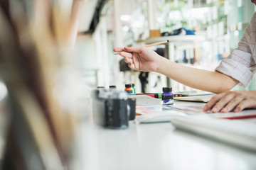 Young asian female designer using graphics tablet while working with computer at studio or office.	